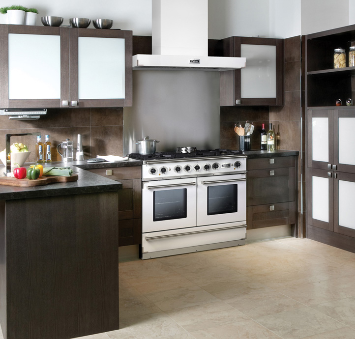 Hochwertige moderne Küche mit dunklen Holzschränken, Gasherd, Dunstabzugshaube und Kücheninsel, auf der frisches Gemüse liegt.