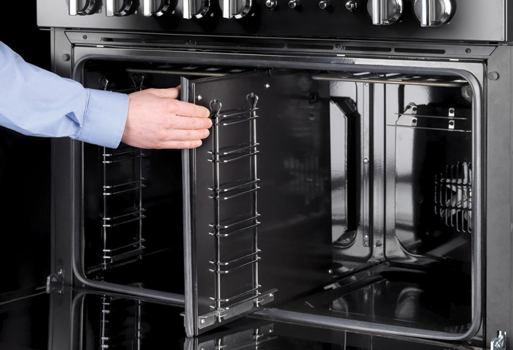 Person öffnet einen modernen Backofen mit zwei Klapptüren, sichtbar sind Roste und Bedienelemente.