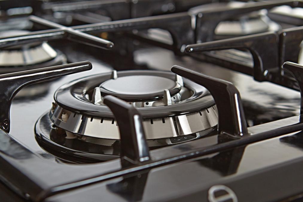 Nahaufnahme eines Gasherds mit glänzendem Edelstahlbrenner und schwarzem Gusseisenrost, ideal für schnelles und präzises Kochen