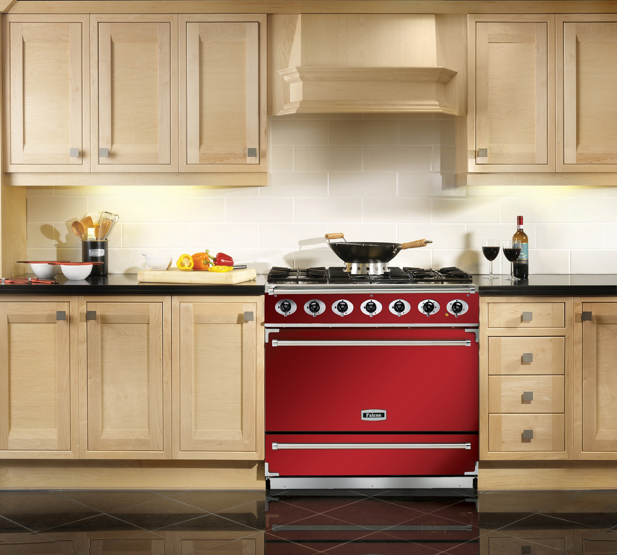 Großer roter Herd mit Gasplatten und Backofen in einer modernen Küche mit hellen Holzschränken, Obst, Wein und Kochutensilien auf der Arbeitsplatte