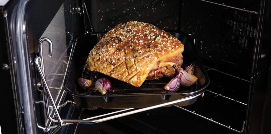 Ein knuspriger Schweinebraten mit Zwiebeln wird im Ofen auf einem Backblech zubereitet