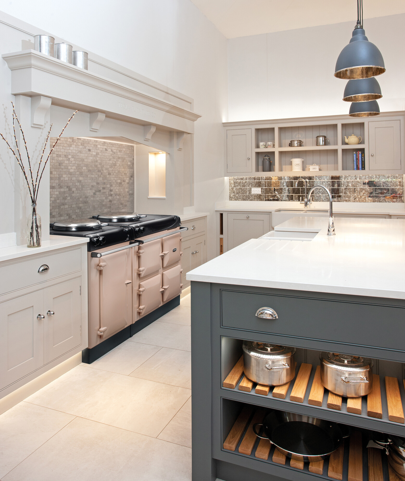 Geräumige, helle Landhausküche mit moderner Kochinsel, integriertem Herd, Küchenschränken, Hängelampen und stilvoller Dekoration