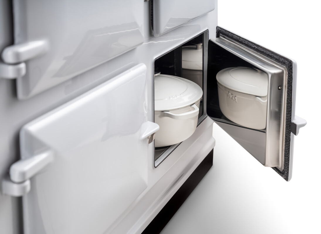 Detailaufnahme eines weißen Bräters in einer geöffneten Backofenkammer eines traditionellen weißen Herdes