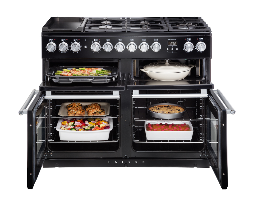 Moderner schwarzer Falcon Herd mit vier offenen Backöfen, gefüllt mit Aufläufen, Kuchen und Gemüse, sowie Gaskochfeld oben