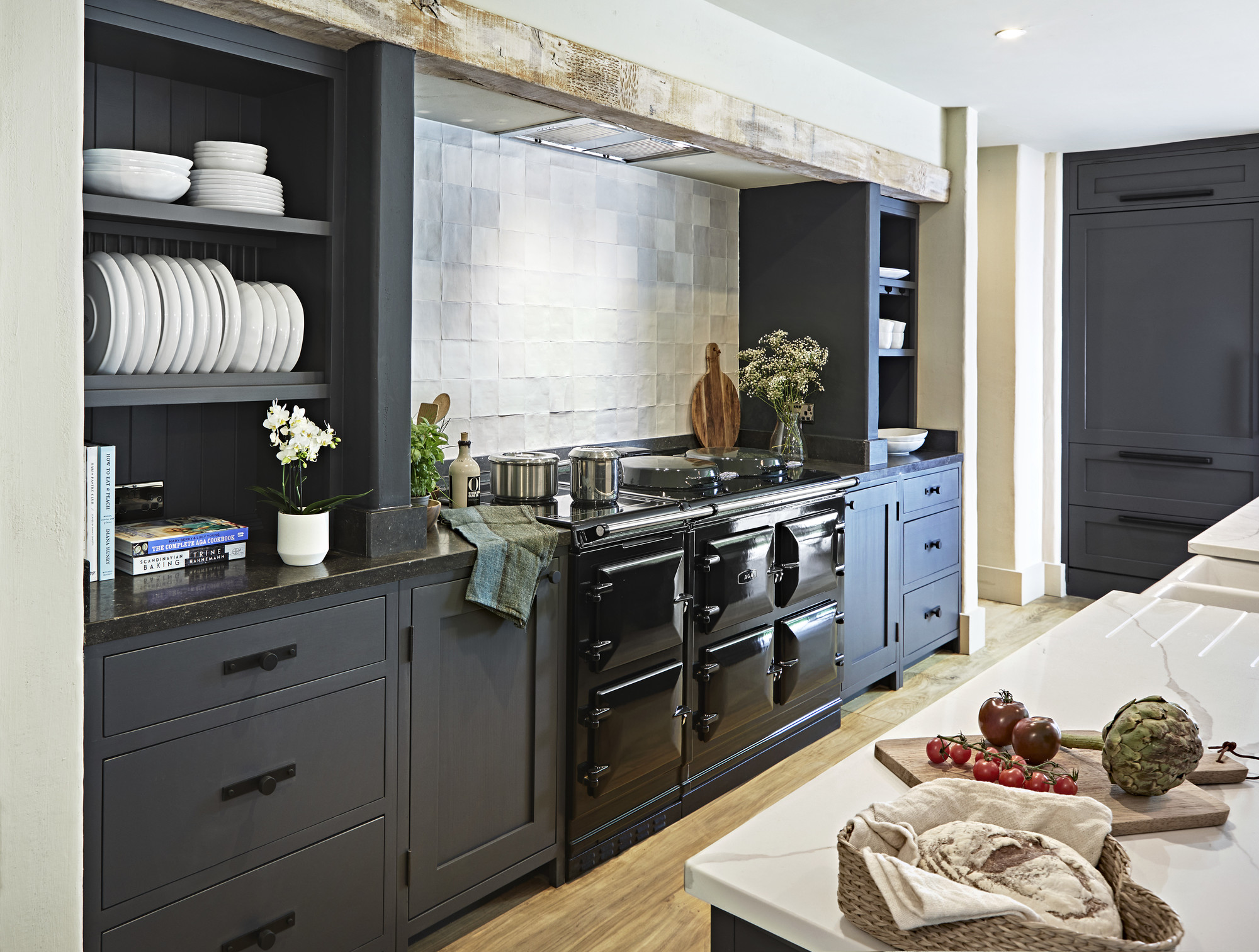Stilvolle, moderne Landhausküche mit schwarzen Schränken, großem Herd, offenem Geschirrregal, Dekopflanzen und frischem Brot auf der Arbeitsplatte